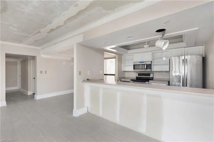 Kitchen featuring pendant lighting, white cabinets, kitchen peninsula, appliances with stainless steel finishes, and crown molding