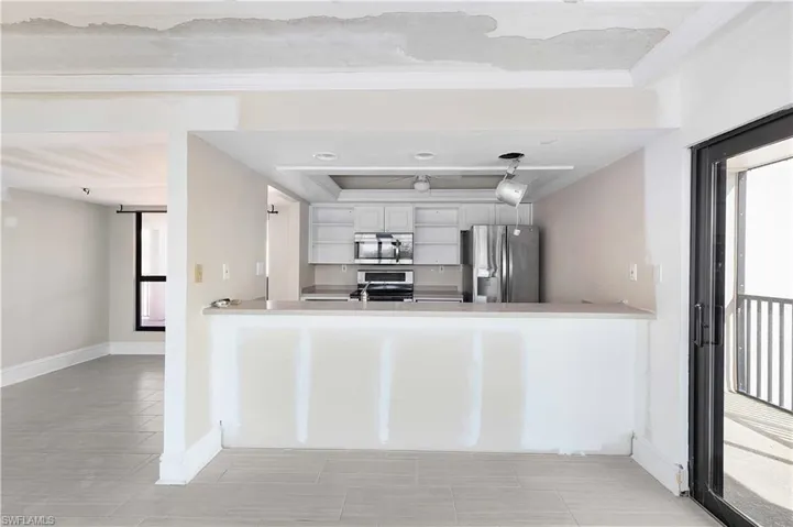 Kitchen with kitchen peninsula, ornamental molding, stainless steel appliances, and white cabinets