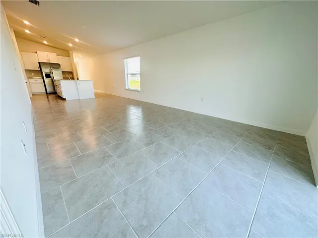 Unfurnished living room with lofted ceiling and light tile patterned flooring