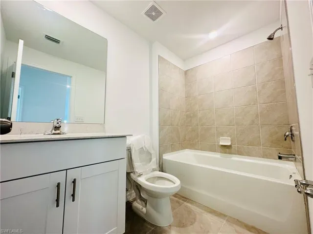 Bathroom featuring vanity, bathtub / shower combination, and light tile patterned floors
