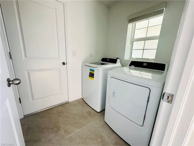 Laundry area featuring washing machine and clothes dryer and light tile patterned floors