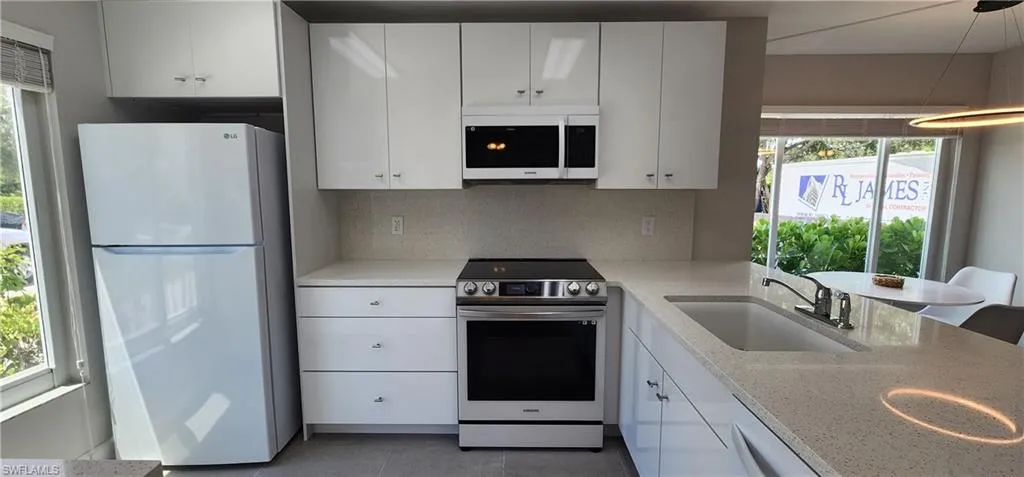 Kitchen featuring stainless steel appliances, sink, tile flooring, and a healthy amount of sunlight