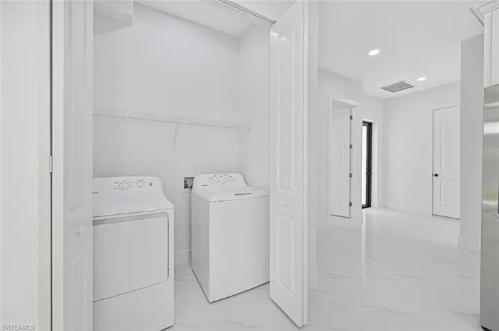 Laundry room featuring light marble finish flooring, independent washer and dryer, and recessed lighting
