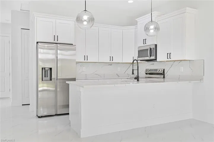 Kitchen featuring tasteful backsplash, white cabinetry, light stone counters, and recessed lighting