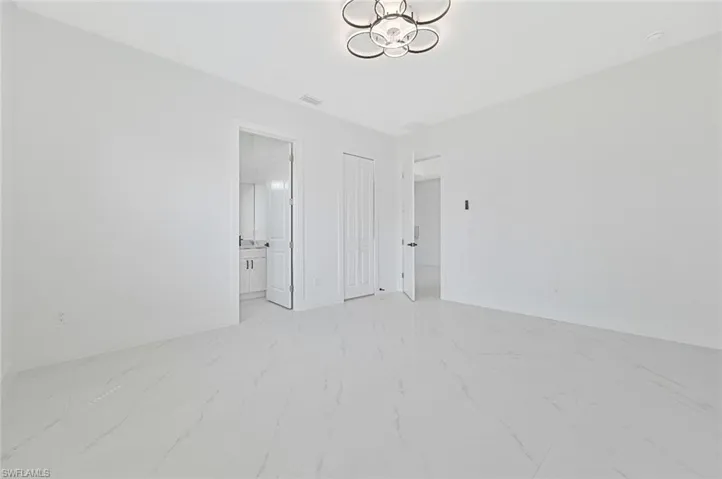 Unfurnished bedroom with light marble finish floors, a closet, and connected bathroom