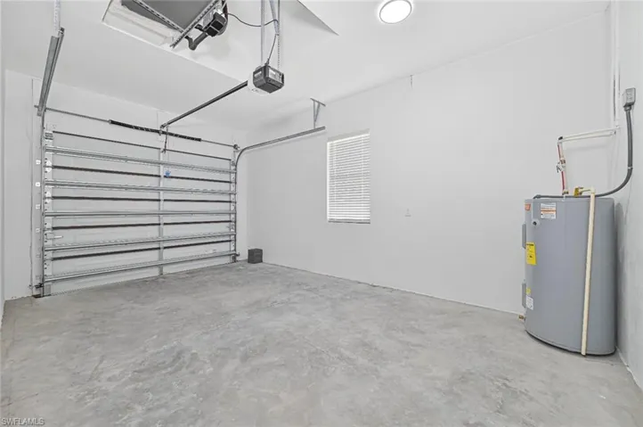 Garage featuring electric water heater and a garage door opener