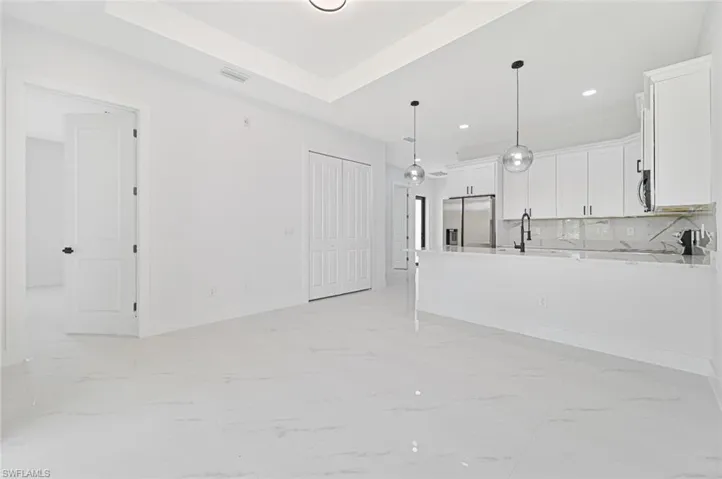 Unfurnished living room featuring light marble finish flooring, recessed lighting, and a tray ceiling