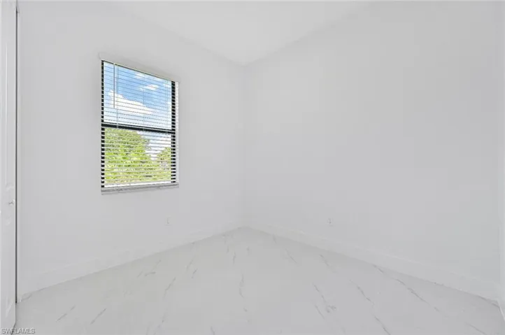 Unfurnished room with baseboards and marble look tiles