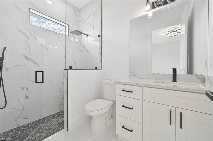 Bathroom featuring a marble finish shower and vanity