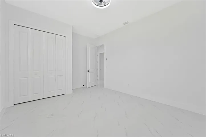 Unfurnished bedroom with a closet and light marble finish floors