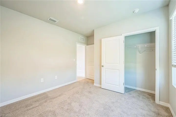 Unfurnished bedroom featuring light carpet and a closet