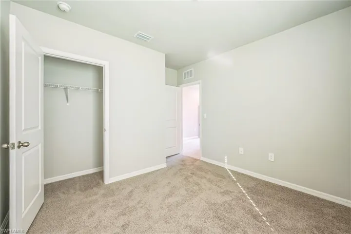 Unfurnished bedroom with light colored carpet and a closet