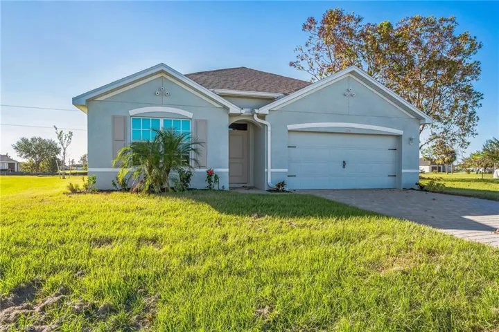 View of front facade with stucco siding, a front yard, driveway, and an attached garage