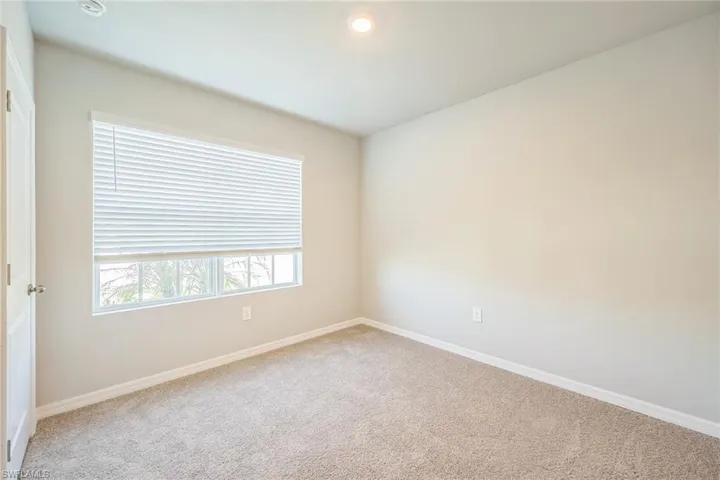Carpeted spare room with baseboards and recessed lighting
