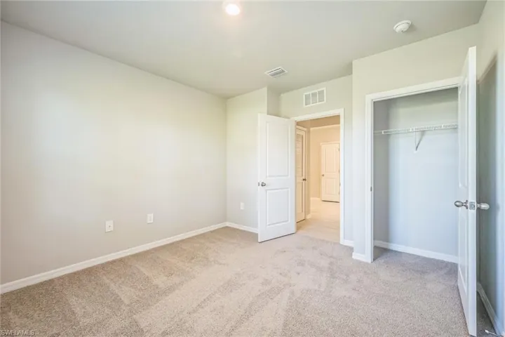 Unfurnished bedroom with light carpet and a closet