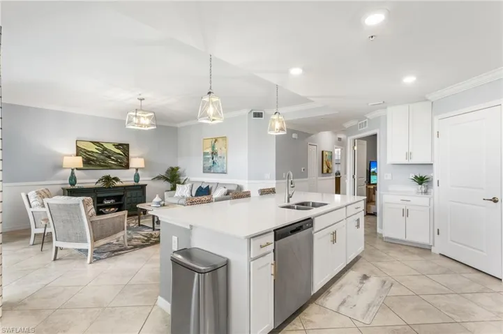 Kitchen with white cabinets, dishwasher, ornamental molding, an island with sink, and light tile patterned floors