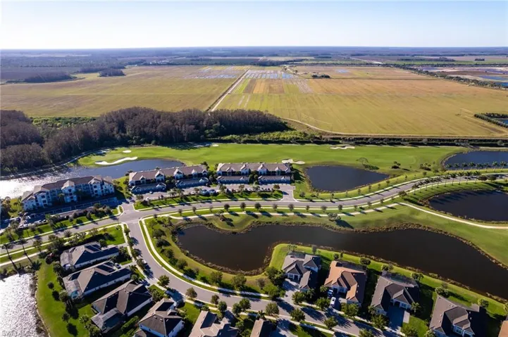 Aerial view of sparsely populated area with a golf course, a nearby body of water, and nearby suburban area
