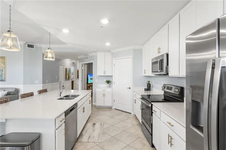 Kitchen featuring stainless steel appliances, a kitchen breakfast bar, white cabinetry, a large island, and crown molding