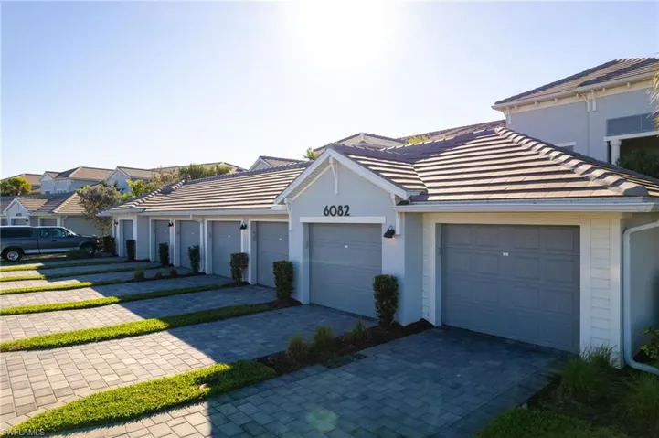 View of front of home with a tiled roof, community garages, a residential view, and stucco siding