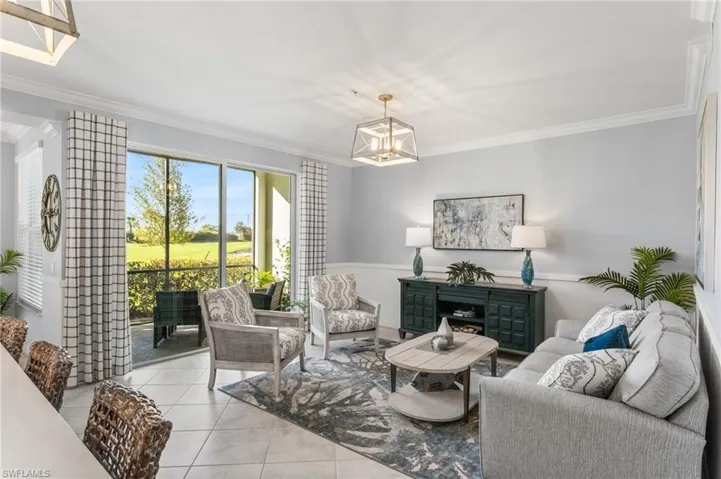Living room featuring crown molding, view of golf course, light tile patterned floors, a chandelier, and a fireplace