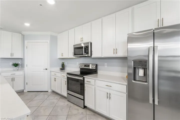 Kitchen featuring stainless steel appliances, white cabinets, crown molding, recessed lighting, and light tile patterned floors