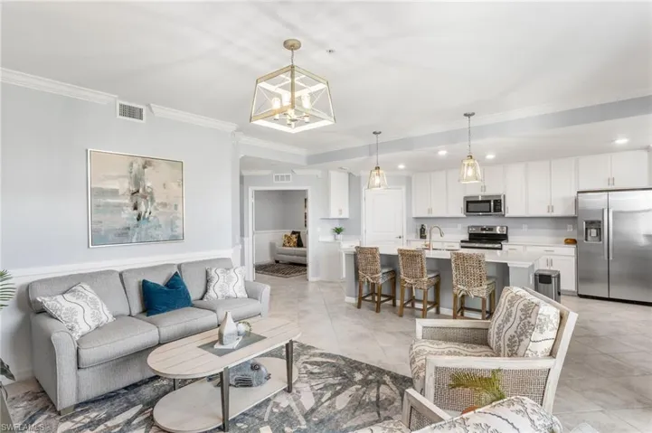 Living area with ornamental molding, hanging lights, and light tile patterned floors