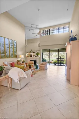 Living room featuring a towering ceiling, light tile patterned floors, ceiling fan, and healthy amount of natural light