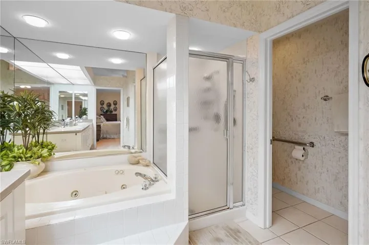 Ensuite bathroom featuring vanity, wallpapered walls, light tile patterned floors, a tub with jets, and a shower stall
