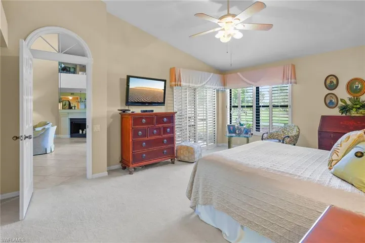 Bedroom featuring vaulted ceiling, carpet floors, a fireplace, and ceiling fan
