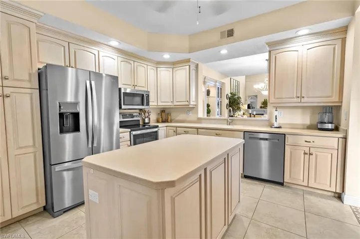 Kitchen with recessed lighting, appliances with stainless steel finishes, light countertops, a center island, and light brown cabinets