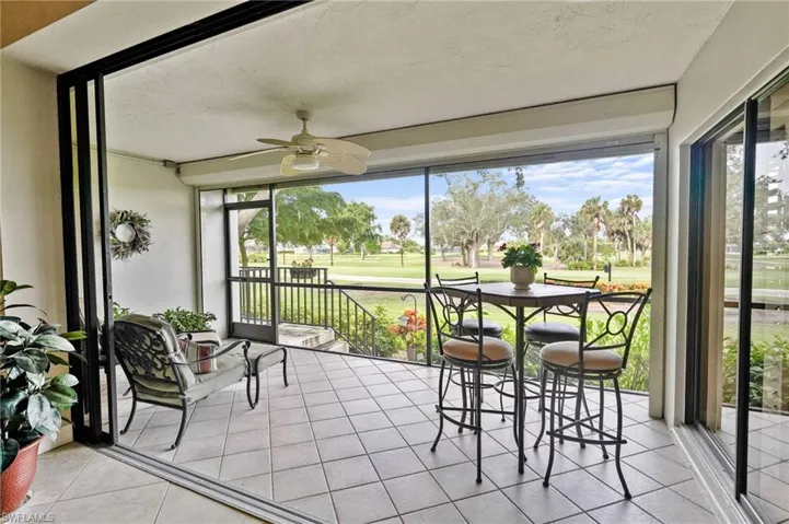 Sunroom / solarium with golf course view, ceiling fan, tile patterned flooring, and a textured ceiling