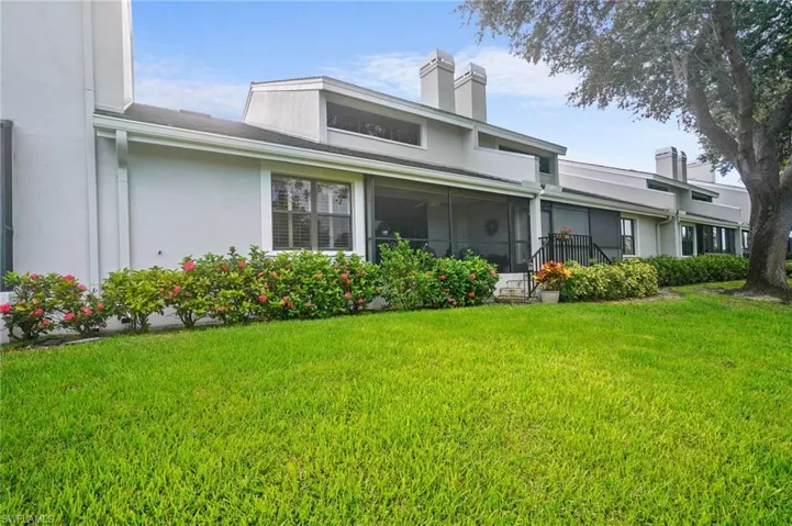 Rear view of property featuring a lawn, a chimney, and stucco siding