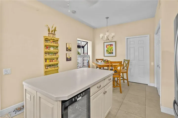 Kitchen featuring a center island, light countertops, pendant lighting, wine cooler, and light tile patterned floors
