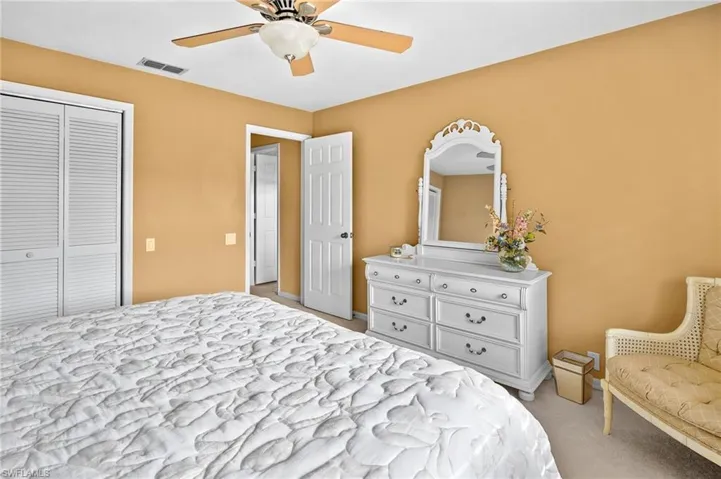 Bedroom with light colored carpet, a closet, and a ceiling fan