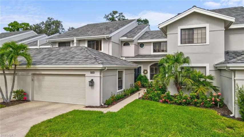Traditional home featuring stucco siding, a front yard, driveway, and an attached garage