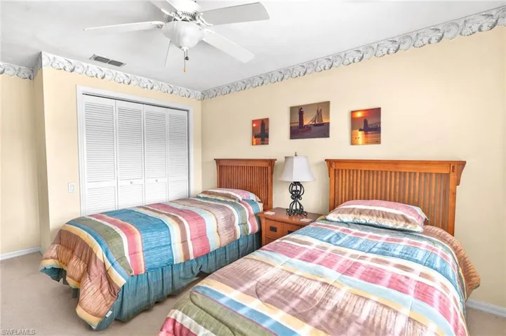 Carpeted bedroom with ceiling fan and a closet