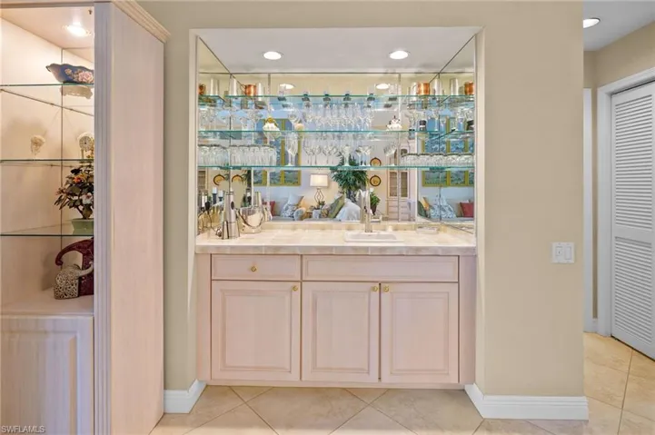 Indoor wet bar featuring light brown cabinetry, recessed lighting, and light tile patterned floors