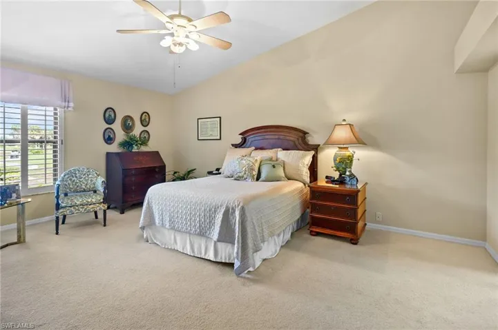 Bedroom with vaulted ceiling, light colored carpet, and a ceiling fan