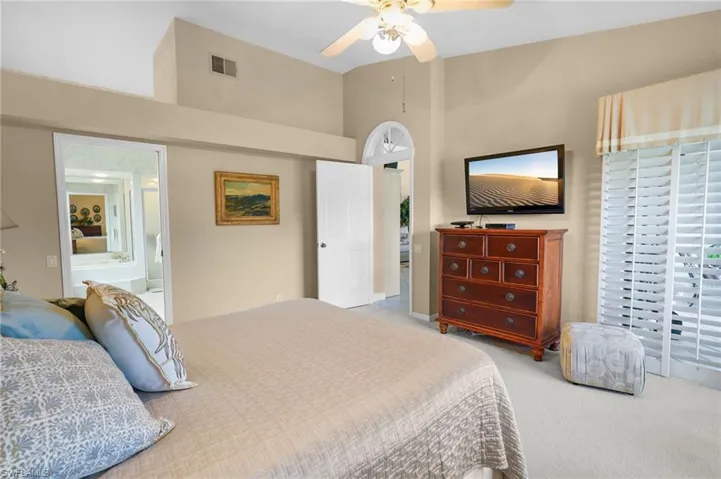 Carpeted bedroom with ceiling fan and high vaulted ceiling