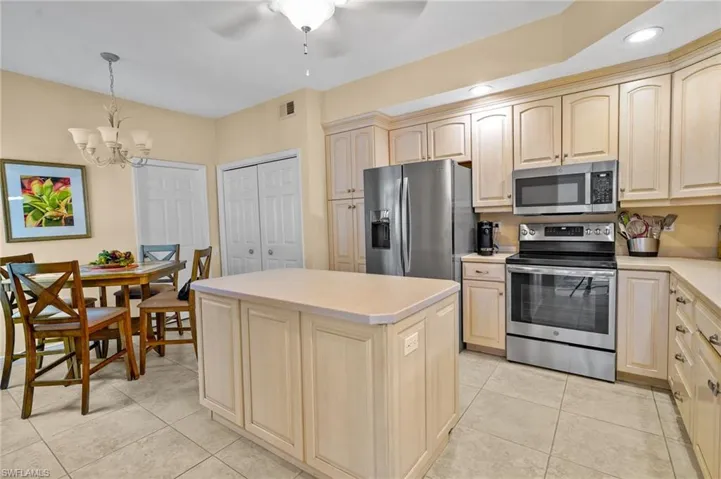 Kitchen featuring appliances with stainless steel finishes, light countertops, pendant lighting, a kitchen island, and light tile patterned floors