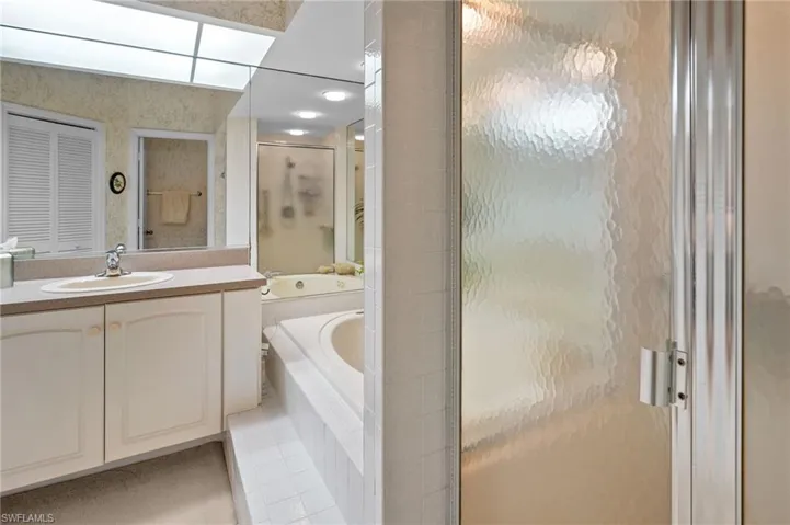 Bathroom featuring vanity, a garden tub, and a shower stall
