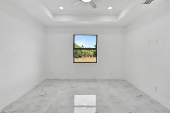 Unfurnished room featuring a raised ceiling, ceiling fan, and recessed lighting