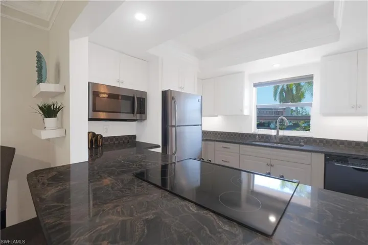 Kitchen with stainless steel appliances, sink, a tray ceiling, and white cabinets