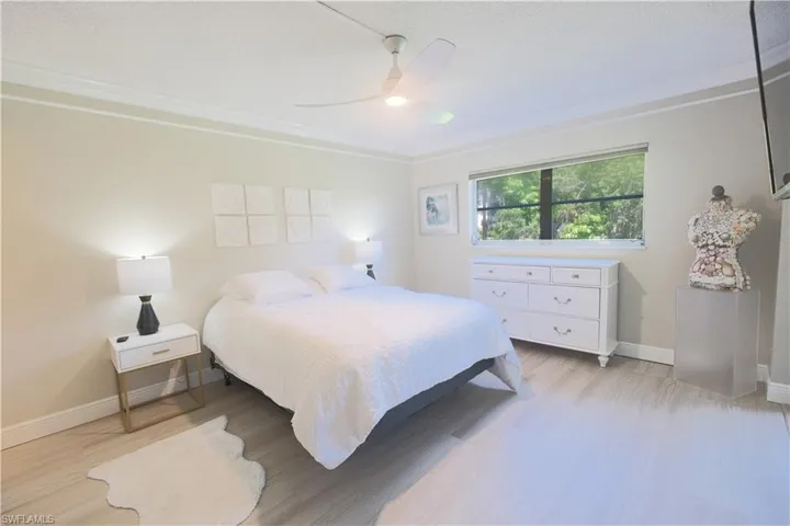 Bedroom with ceiling fan, light hardwood / wood-style floors, and crown molding