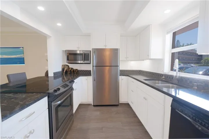 Kitchen with appliances with stainless steel finishes, a tray ceiling, white cabinets, and sink