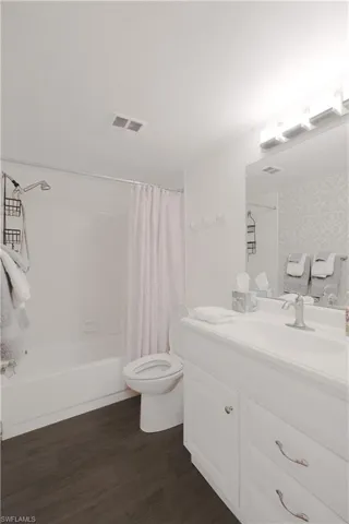 Full bathroom featuring hardwood / wood-style flooring, vanity, toilet, and shower / tub combo