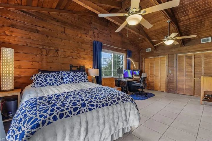 Tiled bedroom featuring wooden ceiling, high vaulted ceiling, wooden walls, ceiling fan, and beamed ceiling