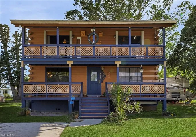 View of front of home with a porch, a balcony, and a front lawn
