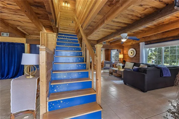 Stairs with wood ceiling, ceiling fan, wooden walls, beam ceiling, and tile patterned flooring