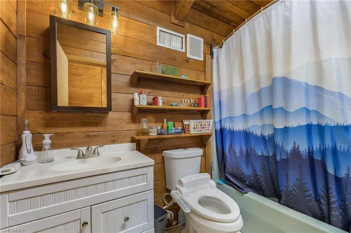 Full bathroom featuring shower / bath combo, toilet, wooden ceiling, and wood walls